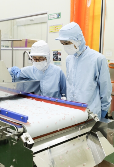 食品の品質チェックを行う作業員たちと製造ライン